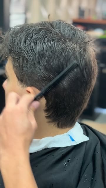 Barbeiro penteando cabelo durante o corte